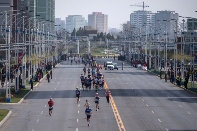 Corredores atravessam a rua dos Cientistas de Mirae durante a maratona de Pyongyang, no Coreia do Norte - 09/04/2017