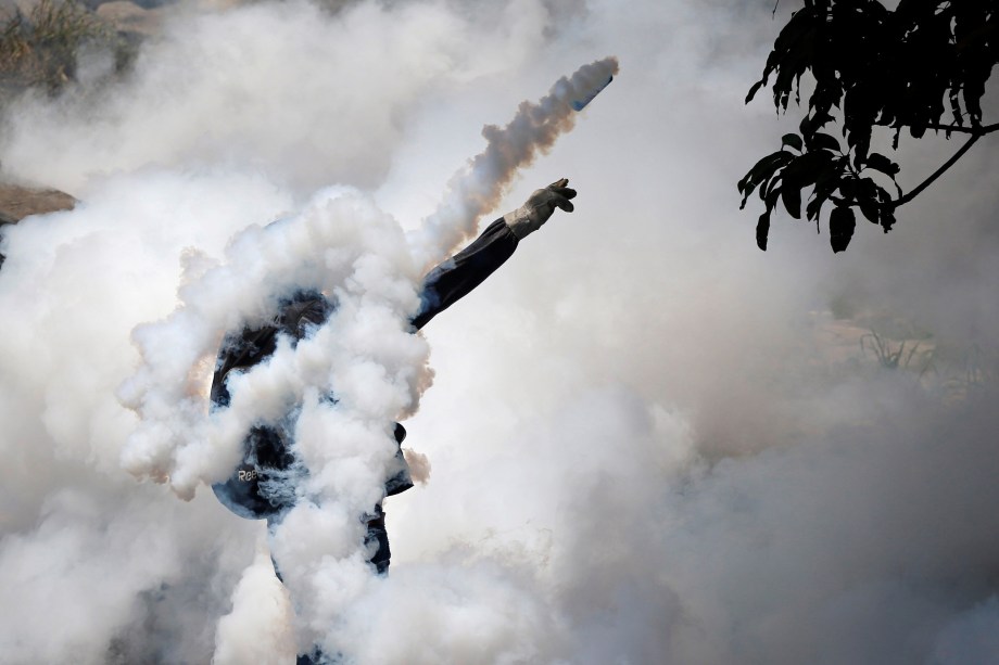 Manifestante arremessa uma granada de gás lacrimogêneo contra a polícia durante protesto de oposição ao presidente da Venezuela, Nicolás Maduro, em Caracas - 19/04/2017