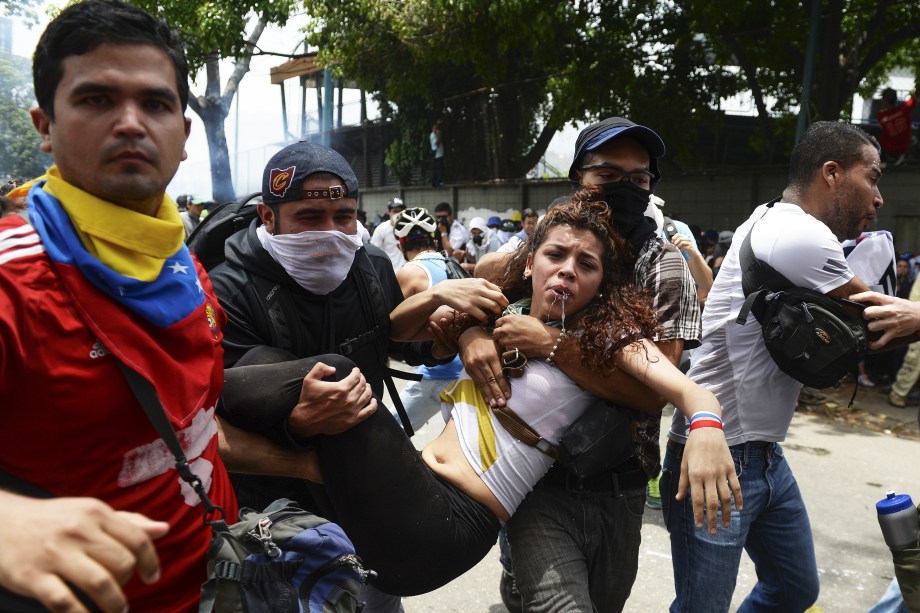 Mulher atingida por gás lacrimogêneo disparado pela polícia é carregada por outros manifestantes durante uma marcha contra o presidente venezuelano, Nicolás Maduro, em Caracas - 19/04/2017