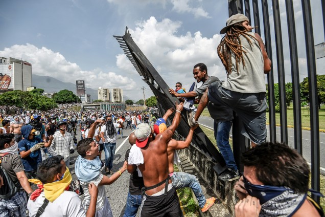 Manifestantes tentam derrubar uma cerca na base aérea de La Carlota durante uma manifestação contra o presidente venezuelano, Nicolas Maduro, em Caracas - 19/04/2017