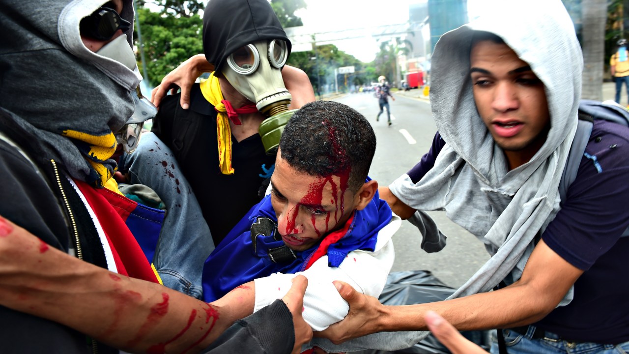 Manifestante ferido é carregado por outros manifestantes que protestavam contra o governo de Maduro, na Venezuela