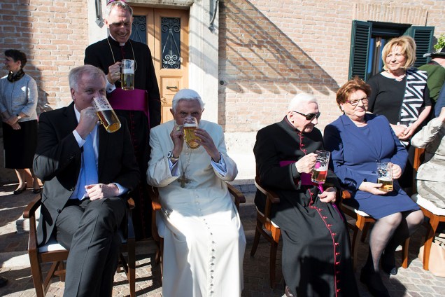 O papa emérito Bento XVI bebe cerveja ao lado de um membro da delegação alemã e do seu irmão e bispo, Georg Ratzinger, no Vaticano. Bento XVI completou 90 anos no domingo (16)