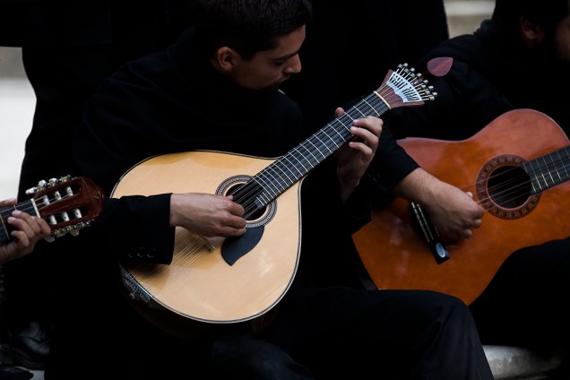 Estudante toca a viola de coimbra durante serenata em parque próximo à universidade de Coimbra