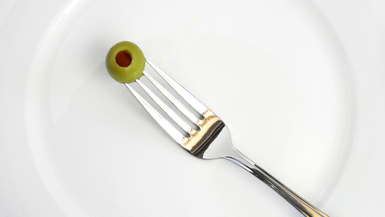 Azeitona espetada com um garfo em um prato branco