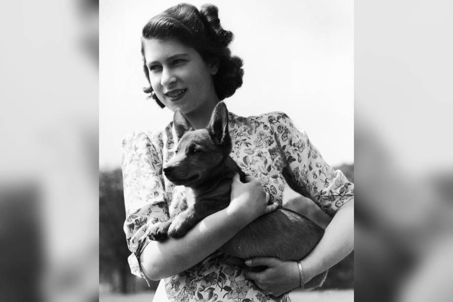 Princesa Elizabeth que segura Sue, um filhote de corgi, no castelo de Windsor em 1944