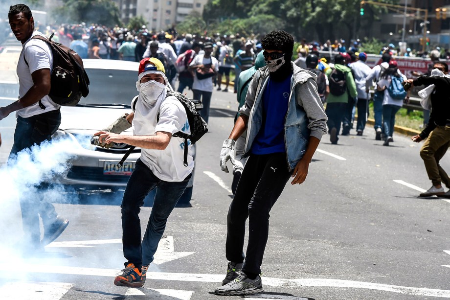 Manifestantes jogam de volta à polícia uma bomba de gás lacrimogêneo durante protesto contra o governo de Nicolás Maduro em Caracas, Venezuela - 04/04/2017