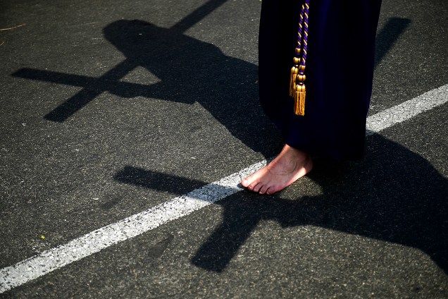 Sombra no asfalto de um penitente descalço da irmandade "Las Cigarreras", que carregava cruz durante uma procissão em Sevilha, Espanha - 13/04/2017