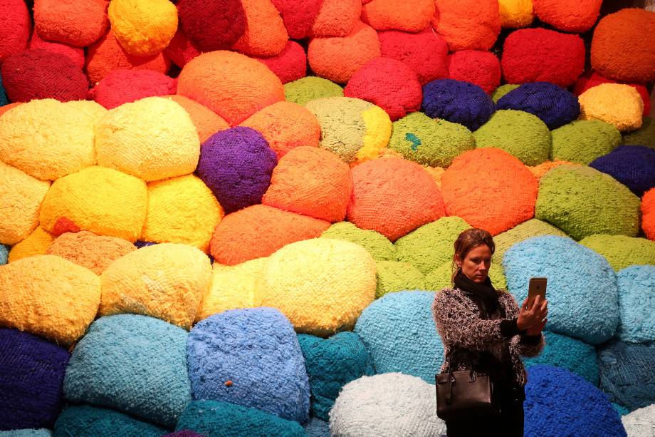 Visitante tira selfie em frente à obra "Escalade Beyonde Chromatic Lands", da artista americana Sheila Hicks, exposta na Bienal de arte de Veneza