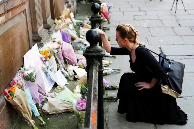 Mulher coloca flores para vítimas de ataque na Arena de Manchester, na Inglaterra -  23/05/2017