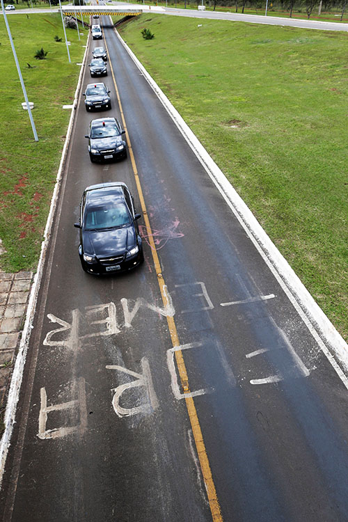 Comitiva do presidente Michel Temer passa sobre uma mensagem de "fora Temer" escrita no asfalto, em Brasília