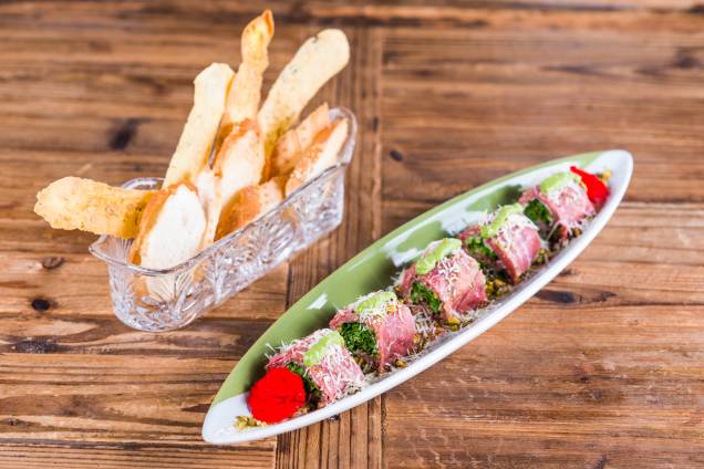 Apresentação delicada do carpaccio com rúcula, pistache, pesto de manjericão e parmesão no Atmã Apresentação delicada do carpaccio com rúcula, pistache, pesto de manjericão e parmesão no Atmã