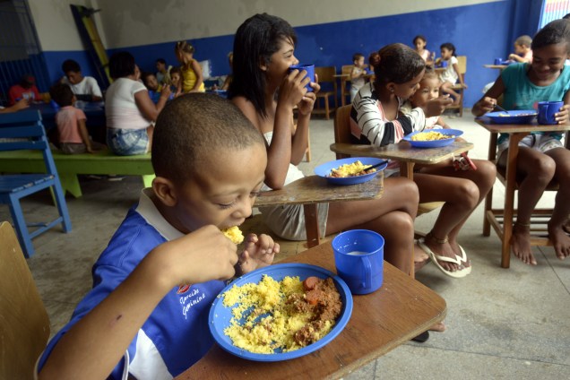 Crianças desabrigadas devido a enchentes, se alimentam em abrigo temporário