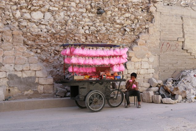 Menino come algodão doce enquanto vende doces em um carrinho em uma rua na cidade de Al-Bab ao norte de Aleppo, na Síria - 15/05/2017