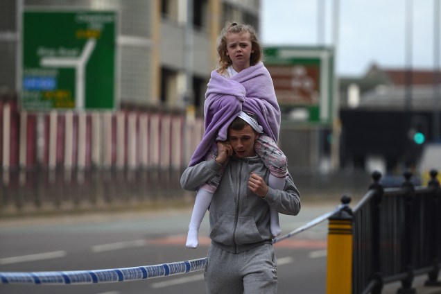 Homem carrega uma criança sobre os ombros nos arredores da estação de Victoria em Manchester, noroeste Inglaterra, na manhã seguinte ao ataque com uma bomba durante show da cantora Ariana Grande - 23/05/2017
