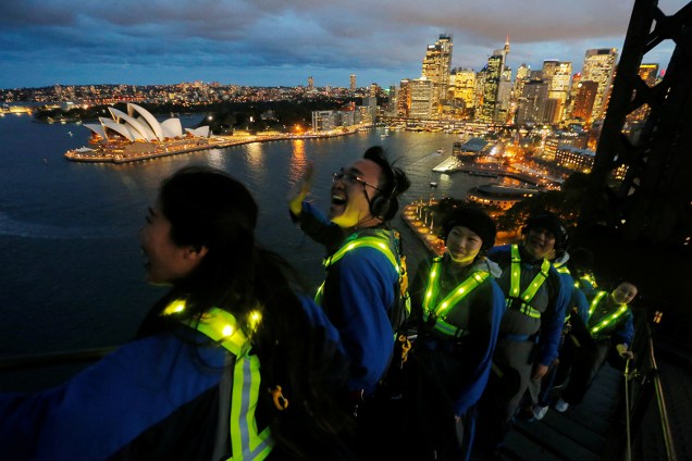 Turitas chineses com roupas fluorescentes visitam o Opera House pela ponte Sydney Harbour, na Austrália - 18/05/2017