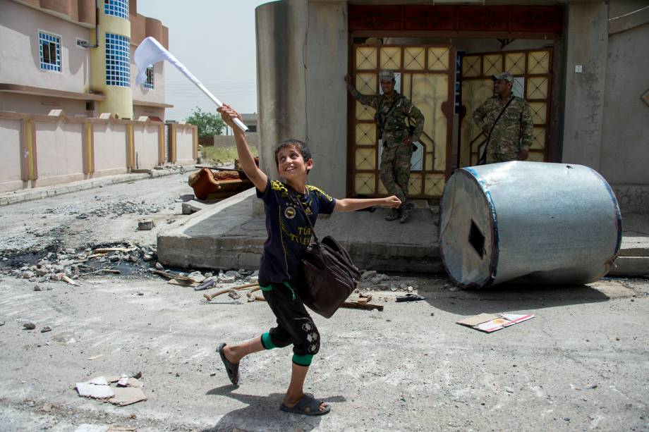 Menino carrega uma bandeira branca enquanto deixa sua casa durante avanço das forças iraquianas no bairro al-Haramat noroeste de Mosul, na ofensiva para retomar a área das mãos dos jihadistas do Estado Islâmico - 11/05/2017