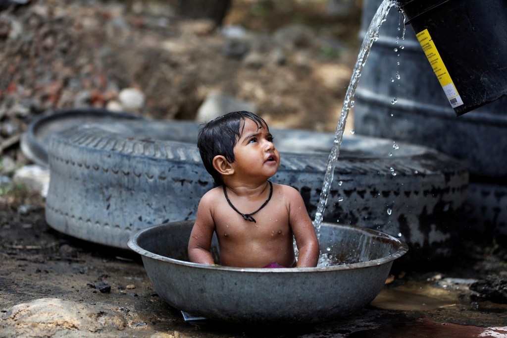 Imagens do dia - Criança se refresca do calor na Índia