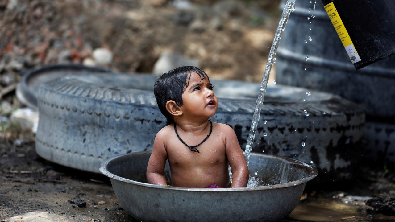 Imagens do dia - Criança se refresca do calor na Índia