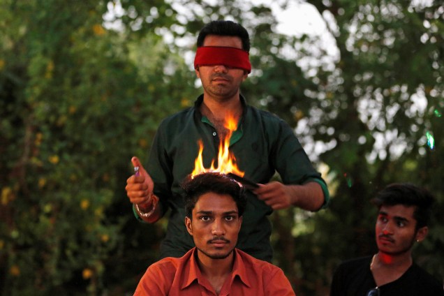 Artista faz cortes de cabelo com fogo em uma praça na região de Ahmedabad, na Índia - 31/05/2017