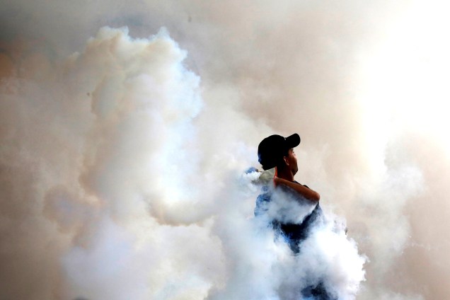 Manifestante joga de volta aos policiais uma bomba de gás lacrimogêneo durante protesto em Caracas, Venezuela, em oposição ao governo de Nicolás Maduro - 04/05/2017