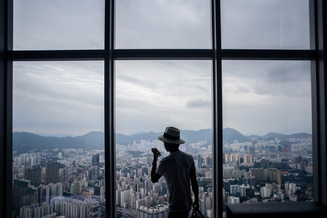 Visitante tira fotos do distrito de Kowloon a partir de um ponto de visualização do Centro de Comércio Internacional em Hong Kong - 16/05/2017
