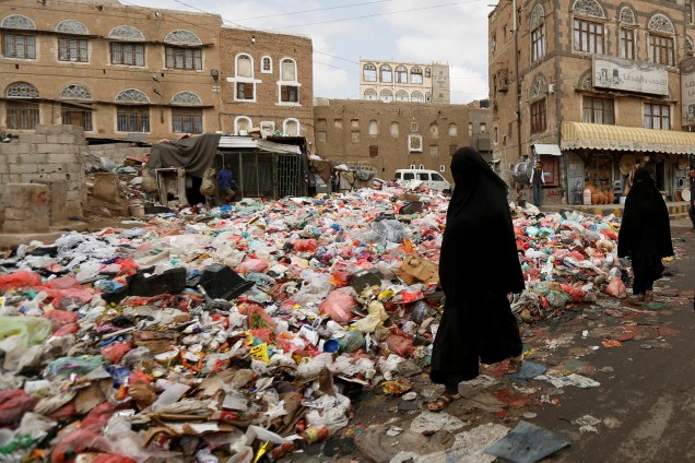Mulheres passam por uma pilha de sacos de lixo em uma rua durante greve de coletores que exigem salários atrasados em Sanaa, no Iêmen - 08/05/2017