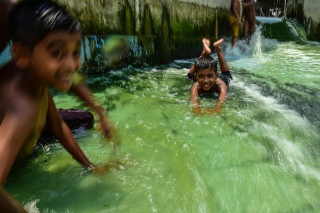 Crianças se divertem em uma piscina para se refrescar do calor em Daca, Bangladesh - 23/05/2017