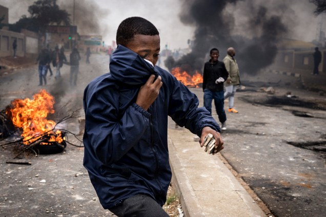 Manifestante cobre o rosto para se proteger do gás lacrimogêneo disparado pela polícia durante um protesto contra falta de moradia e desemprego em Joanesburgo, na África do Sul - 08/05/2017