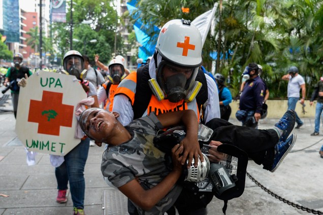 Menino é carregado por um médico após sofrer os efeitos do gás lacrimogêneo durante confrontos entre manifestantes da oposição e a polícia  em um protesto contra o governo do presidente Nicolás Maduro em Caracas, na Venezuela - 30/05/2017
