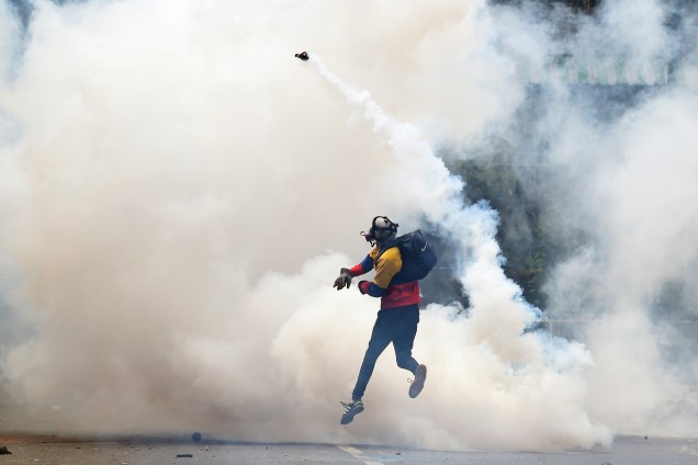 Manifestante de oposição lança uma granada de gás lacrimogêneo em direção à polícia durante protesto contra o presidente Nicolás Maduro em Caracas, na Venezuela - 08/05/2017