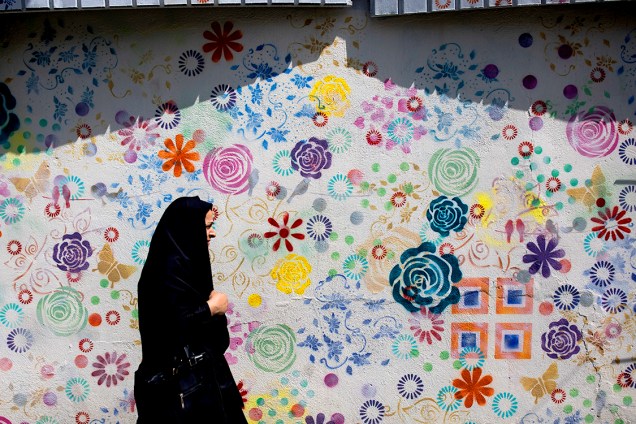 Mulher caminha por um muro grafitado em Teerã, no Irã - 15/05/2017