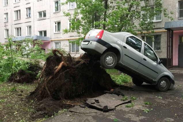 Carro fica suspenso pelas raízes de uma árvore,  derrubada durante uma tempestade em Moscou, na Rússia - 29/05/2017