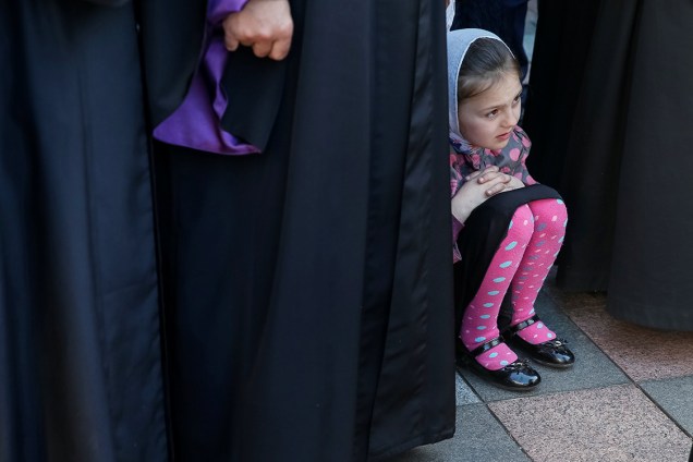 Criança observa atividade de padres ortodoxos durante protesto contra o projeto de lei que daria às autoridades ucranianas mais poder sobre as igrejas, em frente ao Parlamento, em Kiev - 18/05/2017