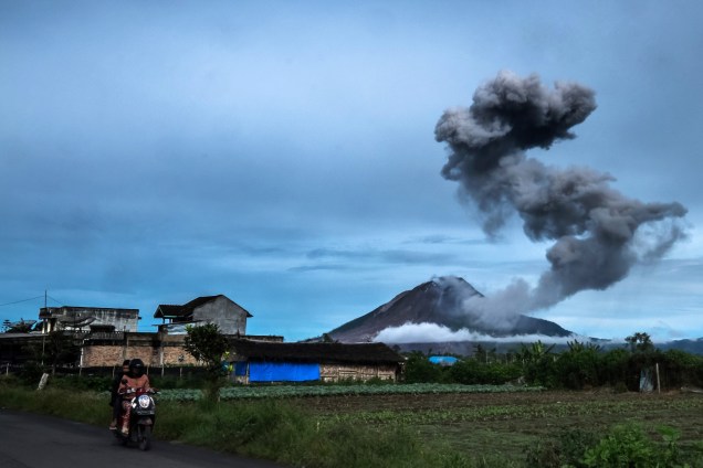 Motociclista atravessa uma estrada enquanto o vulcão do monte Sinabung expele cinza vulcânica, em imagem registrada a partir da vila de Tangkulen em Karo, na Indonésia - 12/05/2017
