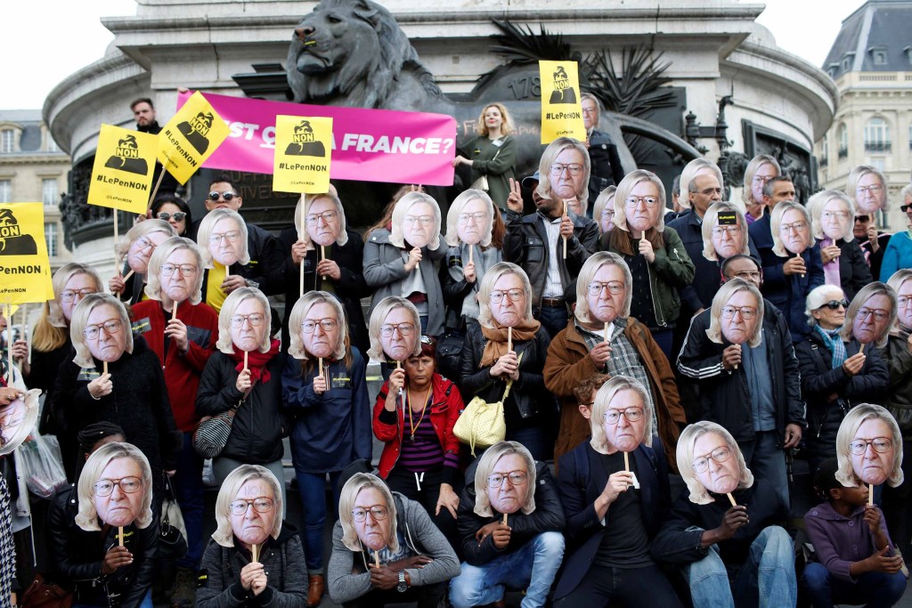 Manifestantes contrários à Frente Nacional mostram máscaras com Jen-Marie Le Pen com o cabelo da filha, Marine