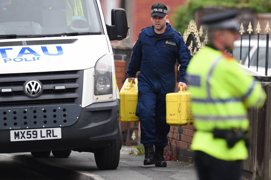 Oficiais de polícia carregam equipamentos forenses enquanto chegam em uma propriedade residencial durante as investigações sobre o ataque terrorista durante show na cidade de Manchester, na Inglaterra - 24/05/2017