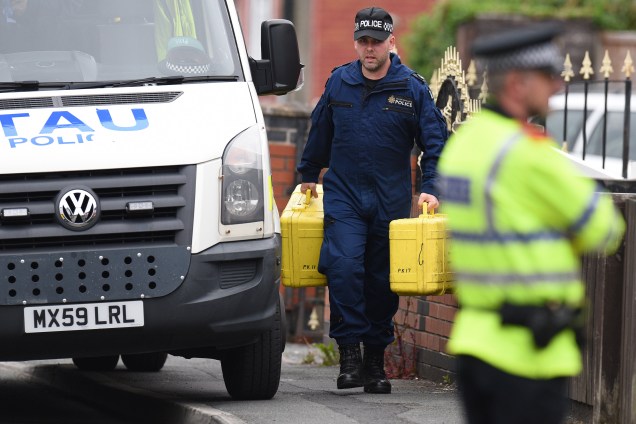 Oficiais de polícia carregam equipamentos forenses enquanto chegam em uma propriedade residencial durante as investigações sobre o ataque terrorista durante show na cidade de Manchester, na Inglaterra - 24/05/2017
