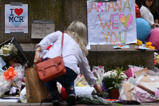 Mulher coloca flores em um memorial improvisado às vítimas do ataque terrorista durante show Manchester Arena, na praça de St Ann em Manchester, na Inglaterra - 24/05/2017