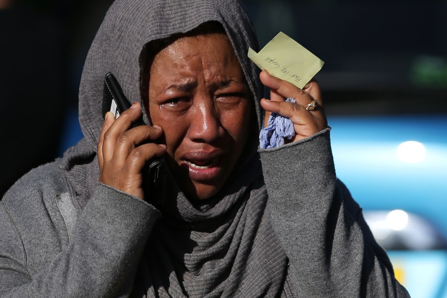 Ao telefone, uma mulher chora desesperada na tentativa de localizar um parente desaparecido e que teria sido afetado pelas chamas do Grenfell Tower, no oeste de Londres - 14/06/2017