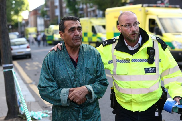 Um policial ajuda a evacuar a área próxima da tragédia ocorrida em Latimer Road, no oeste de Londres - 14/06/2017