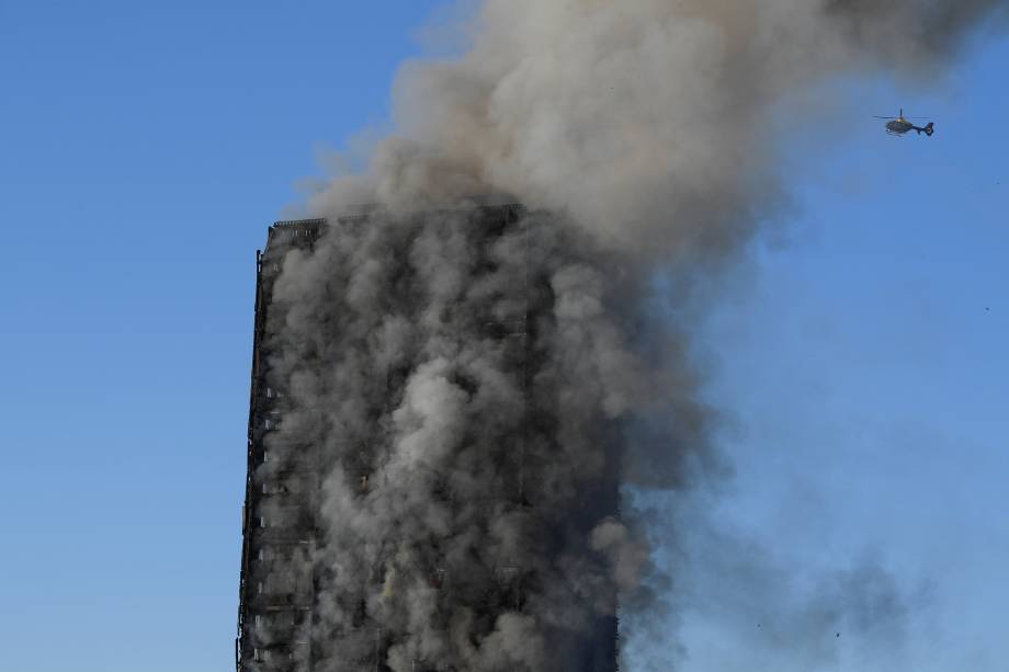 Helicóptero sobrevoa o Grenfell Tower após o fogo ter devastado boa parte do prédio - 14/06/2017