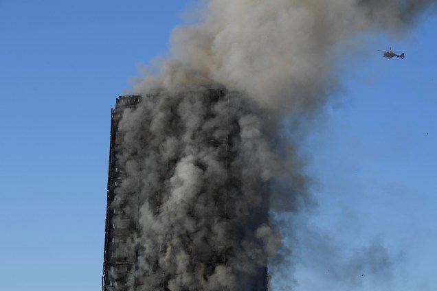 Helicóptero sobrevoa o Grenfell Tower após o fogo ter devastado boa parte do prédio - 14/06/2017