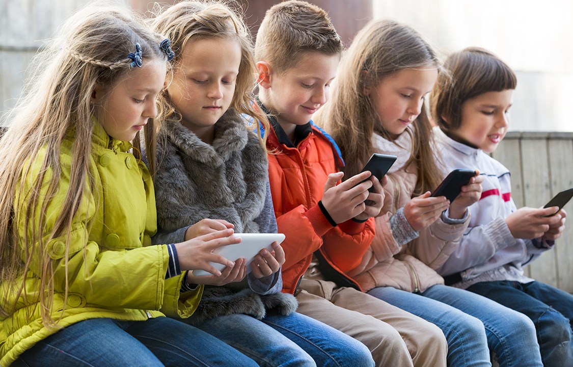 Crianças brincando com celulares e tablets