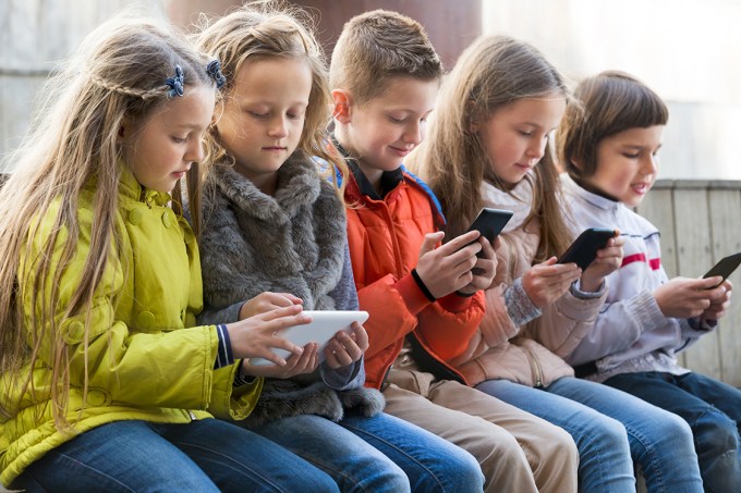 Crianças brincando com celulares e tablets