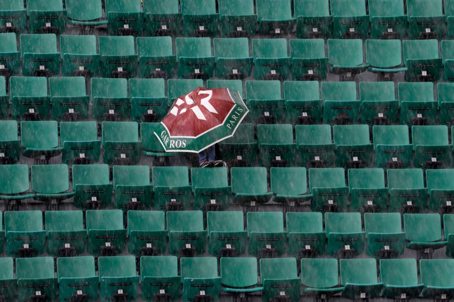 Espectador se protege da chuva na quadra Philippe Chatrier durante o torneio de Roland Garros em Paris. Anualmente a competição é afetada pelas condições climáticas - 06/06/2017