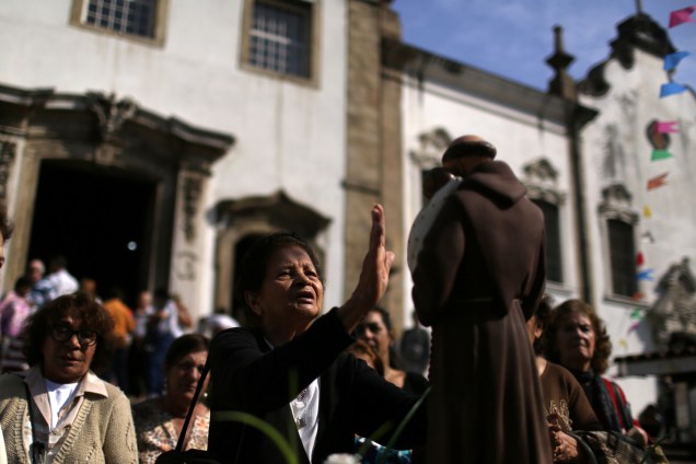 Fiéis rezam em frente a igreja diante de uma imagem de Santo Antônio, protetor dos pobres, no Rio de Janeiro