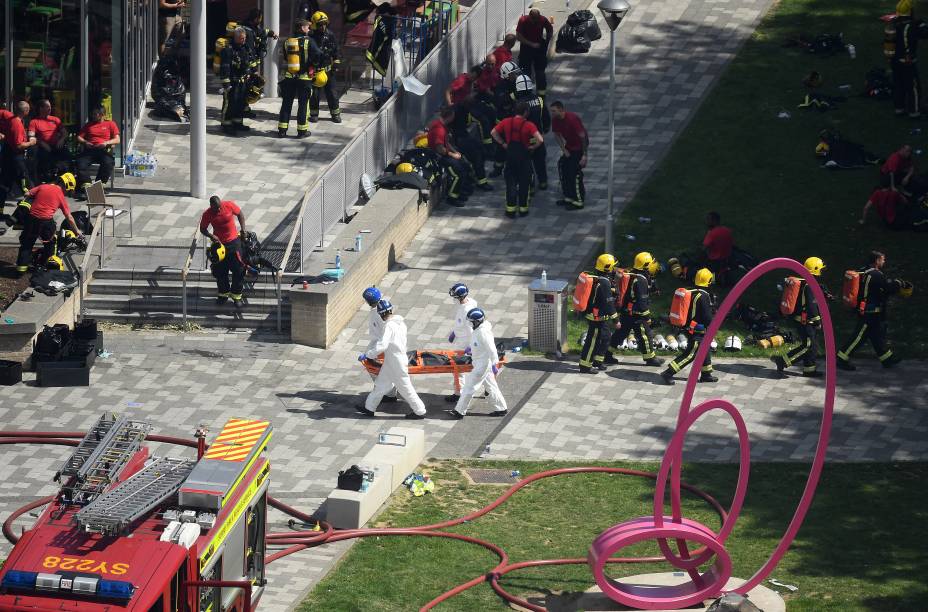 Equipe de emergencia do corpo de bombeiros, policiais e demais ajudantes ao lado do local do incêndio no Grenfell Tower, em Londres - 14/06/2017