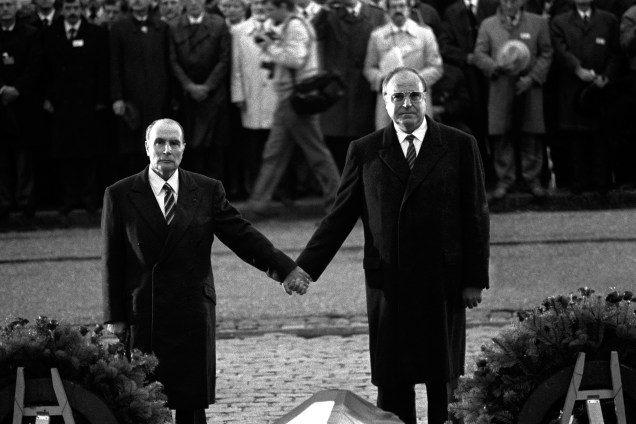O chanceler alemão Helmut Kohl e o presidente francês François Mitterrand unem as mãos para reafirmar a reconciliação franco-alemã, durante  cerimônia em memória das vítimas da Segunda Guerra Mundial em Verdun, Leste da França no ano de 1984