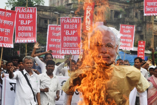 Agricultores e ativistas queimam um retrato do primeiro-ministro Narendra Modi durante um protesto contra o governo e as mortes de fazendeiros no estado de Madhya Pradesh, em Calcutá, na Índia - 19/06/2017