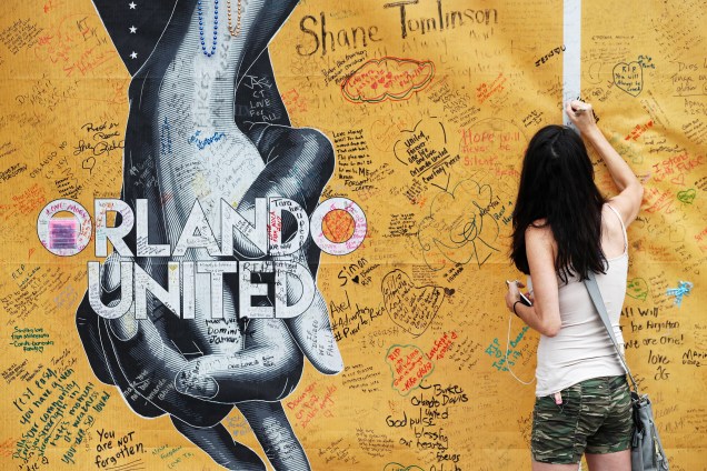 Mulher assina um mural do lado de fora da boate Pulse em um memorial dedicado às vítimas do tiroteio em Orlando, Flórida no aniversário de um ano do atentado que deixou 49 mortos - 12/06/2017